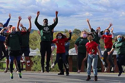 The 多样性中心 and 包容 工作人员 outside on the upper quad jumping in the air in a celebratory manner.. 