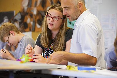 A student 和 fine arts professor in a classroom discussing a project. 