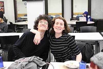 A female student and a male student smile for the camera during a dinner for students who participate in Center for 多样性 and 包容 activities. The female student on the left has her arm around the male student. 