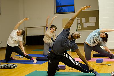 Landmark College students do a side stretch during a yoga class.